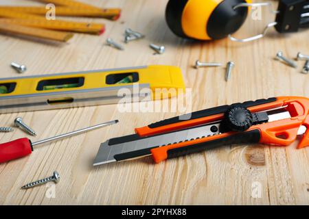 Utility knife and different tools on black textured table, closeup ...
