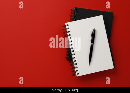 Notebooks and pen on red background, top view. Space for text Stock Photo
