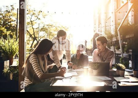 The good ideas are right in from of him. a group of colleagues having a meeting outside at a cafe. Stock Photo