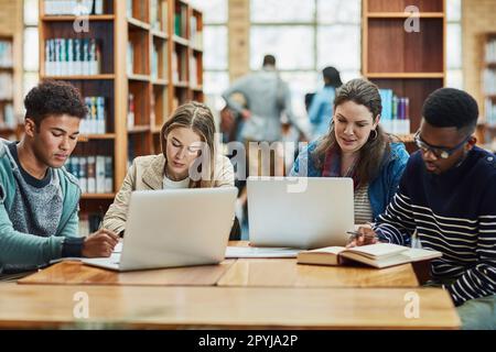 Staying fully engaged in their education. a group of university students working in the library at campus. Stock Photo