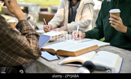 Cropped image, Group of college students preparing for the exam, doing homework or school project together at a campus park. Stock Photo