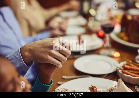 Be grateful for your abundance of blessings. Closeup shot of people holding hands in prayer before having a meal together. Stock Photo