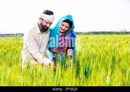 Happy young indian farmer couple showing smart phone with blank display ...
