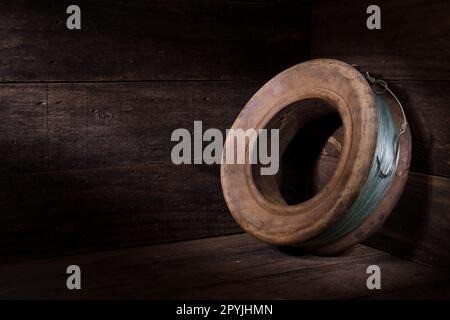 A still life of an old wooden hand fishing reel with line and a rusty