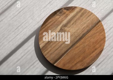 photo round wooden board on a white table with a shadow of a window on it top view Stock Photo