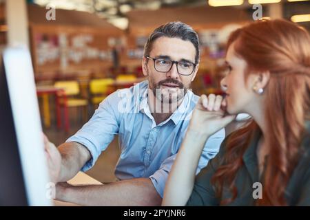 Working on a big plan together. two designers working together on a computer in an office. Stock Photo