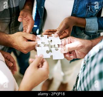 All our ideas brings us to the solution. a group of creatives connecting pieces of a puzzle. Stock Photo