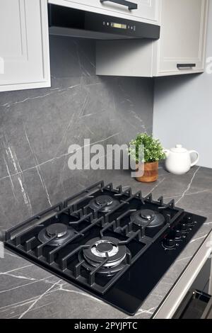 Modern built-in four-burner gas stove with black metal grates on a ...