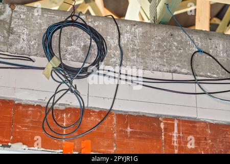 Electric power cables prepared for installation on new house construction site wall Stock Photo