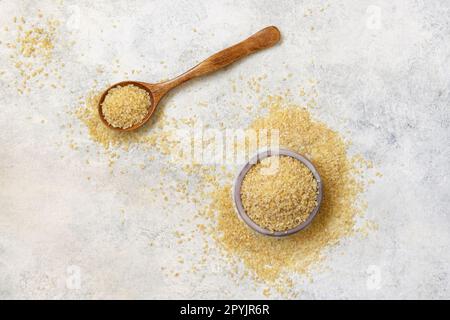 Wooden scoop and bowl with Dry uncooked bulgur wheat grain top view. Healthy food Stock Photo