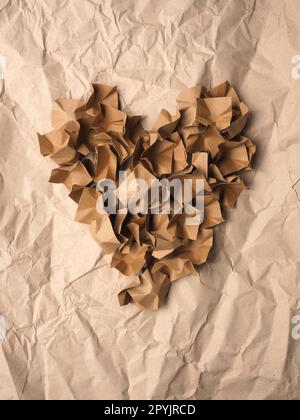 Heart shape made from recycled paper packaging material on a crushed recycled paper Stock Photo