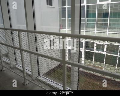 New white frames and windows. Metal fence for the safety of schoolchildren. New modern school. View from the window to the opposite wall and windows. Security systems. Internal office interior. Stock Photo