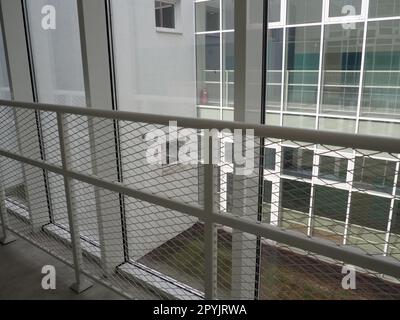 New white frames and windows. Metal fence for the safety of schoolchildren. New modern school. View from the window to the opposite wall and windows. Security systems. Internal office interior. Stock Photo