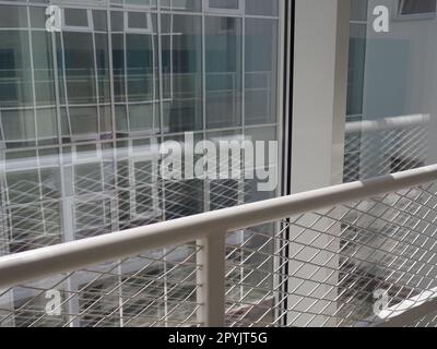 New white frames and windows. Metal fence for the safety of schoolchildren. New modern school. View from the window to the opposite wall and windows. Security systems. Internal office interior. Stock Photo