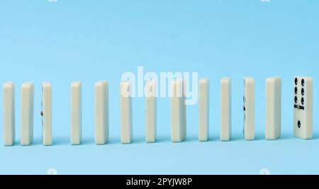 Dominoes standing in a row on a blue background, gambling Stock Photo