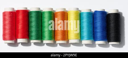 Multicolored spools of sewing threads on a white background, top view Stock Photo