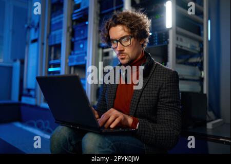 Network engineer using digital tablet in server room during maintenance work Stock Photo