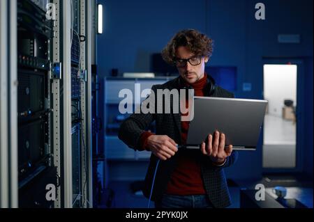 IT technician switching wire to laptop computer Stock Photo