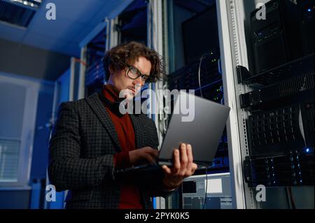 IT technician using digital tablet while working in data center with server rack Stock Photo
