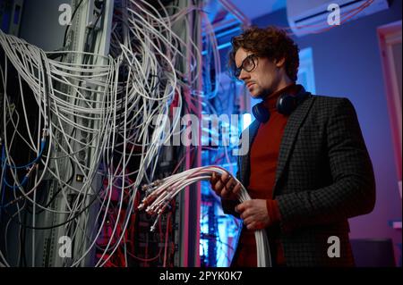 IT man with bunch of cables in hands in server room Stock Photo