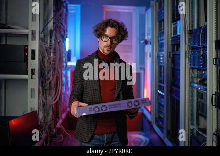 Portrait of it specialist holding hardware in hand standing in server room Stock Photo