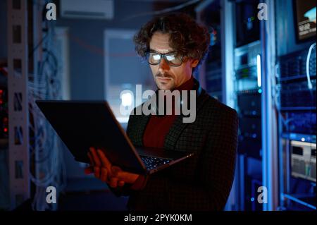 IT technician checking the servers vitals using laptop computer Stock Photo