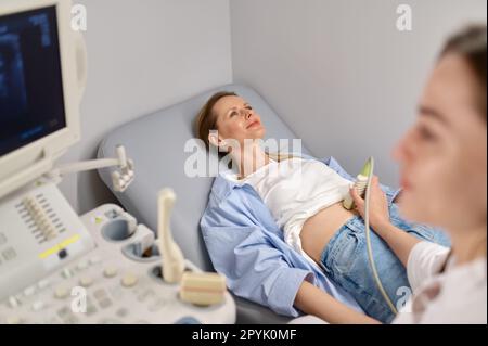 Professional doctor examining his patient doing abdominal ultrasound Stock Photo