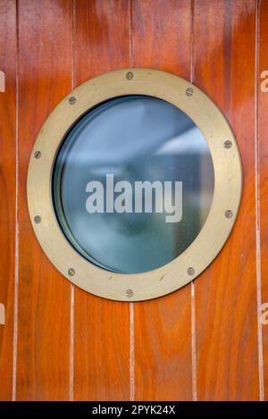 A porthole on a door on a ship. Stock Photo