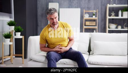 Man Suffering From Stomach Ache Sitting Stock Photo