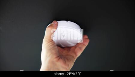 Person's Hand Installing Smoke Detector On Ceiling Wall Stock Photo