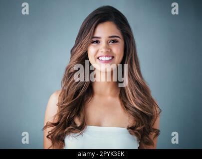 Simply, stunning. Studio portrait of a beautiful young woman posing against a gray background. Stock Photo