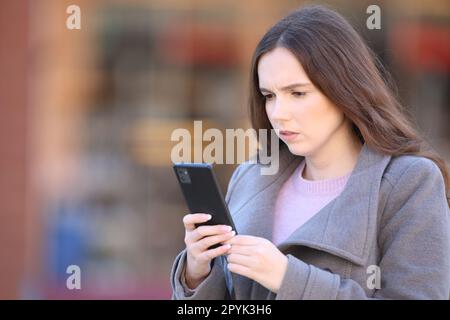 Worried woman using phone in the street in winter Stock Photo