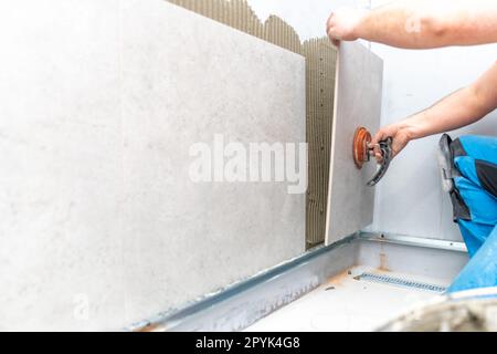 installation of large format tiles on the wall by a craftsman Stock Photo
