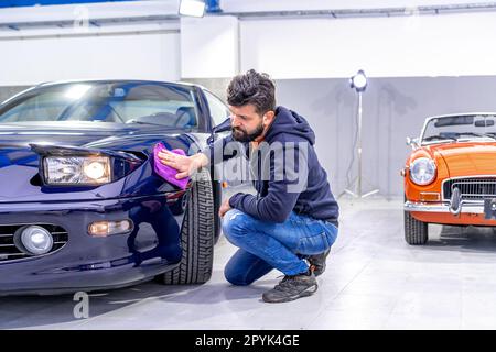 detailing and polishing the body of a luxury sports car using a micro fiber. flip-up car light Stock Photo