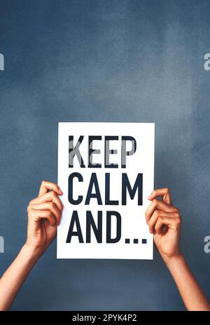 No need to get worked up. Studio shot of an woman holding a sign that says keep calm against a blue background. Stock Photo