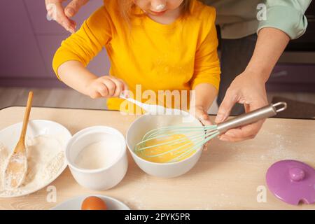 Grandmother and granddaughter prepare cake dough, spend time together, family relationships, love. spoon with sugar. Stock Photo