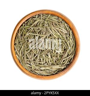Dried rosemary leaves, fragrant needle-like green leaves, in wooden bowl Stock Photo