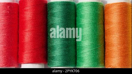 Multicolored spools of sewing threads on a white background, top view Stock Photo