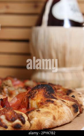 Fresh Pizza on Wooden Table at Restaurant With Bottle of Chianti Wine in Background Stock Photo