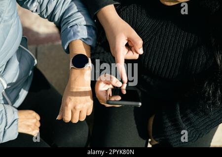 three Latin people using their mobile devices and interacting with each other Stock Photo