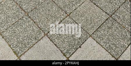 Stone tiles with dark and light finish. Squares or rhombuses photographed diagonally. Chess tile. Rough rocky surface. Tiles on the road. Stock Photo
