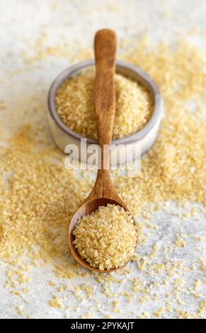 Wooden scoop and bowl with Dry uncooked bulgur wheat grain close up. Healthy food Stock Photo