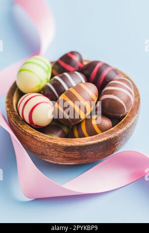 Chocolate easter eggs in bowl on blue background. Stock Photo