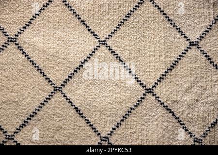 Beige fabric texture. Close-up of a light brown carpet textile background with a pattern of squares. Macro photograph. Beautiful bright backdrop with space. Stock Photo