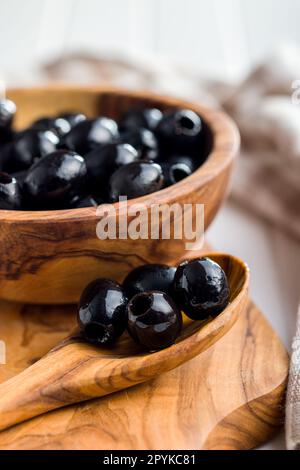 Pitted black olives in wooden spoon. Stock Photo