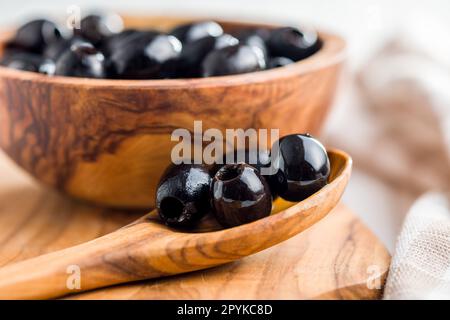 Pitted black olives in wooden spoon. Stock Photo