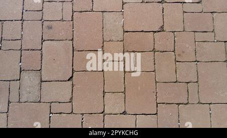 Cobbled street of the old city, lined with square and rectangular stone tiles in a chaotic manner. Soft beige, brown and gray colors and tones. The texture of the stone. Geometric pattern. Stock Photo