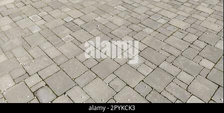 Cobbled street of the old city, lined with square and rectangular stone tiles in a chaotic manner. Soft gray color. The texture of the stone. Geometric pattern. Stock Photo