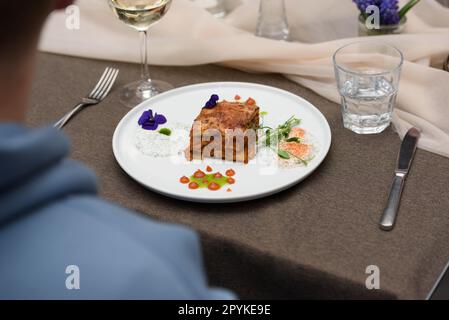 portion of traditional greek moussaka in white plate on a table in a restaurant Stock Photo