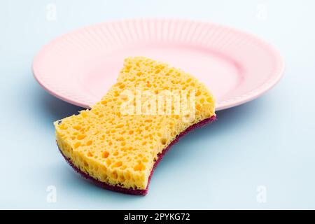 Sponge for washing dishes on the plate on blue background. Stock Photo